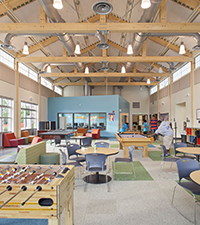 Modern clubhouse interior with tables, seating areas, games, and open event space