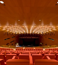 Large convention center auditorium with rows of seats facing a stage for corporate events