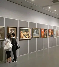 Visitors viewing framed artwork displayed along the walls of a modern cultural center