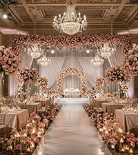 Decorated marriage hall with floral arrangements, tables, and an elegant wedding stage