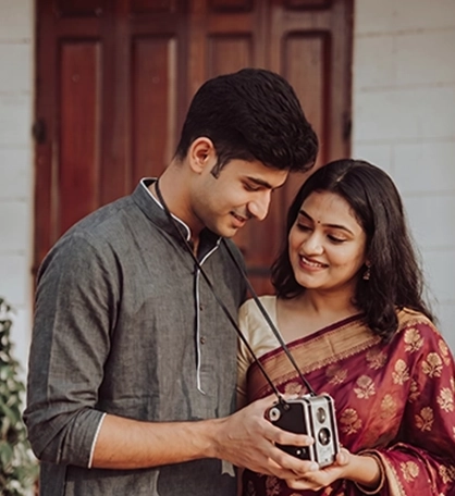 Couple enjoying a relaxed pre-wedding shoot while looking at a vintage camera together