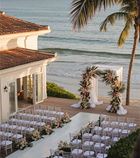 Outdoor resort wedding setup beside the sea with decorated chairs and floral arch