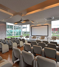 Seminar hall arranged with rows of chairs, presentation screen, and conference tables