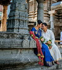 Couple in traditional wedding attire posing together at a historic temple for portraits