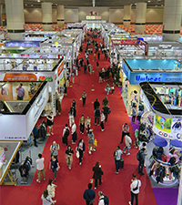 Busy trade show venue with exhibition booths and visitors walking through aisles